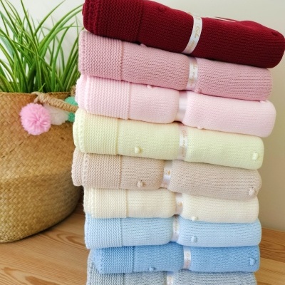 Pilhas de mantas de malha coloridas com pompons e bolsa de palha com planta