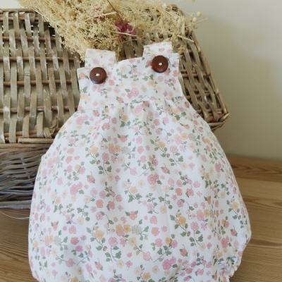 Macacão de bebé branco com padrão floral e botões castanhos