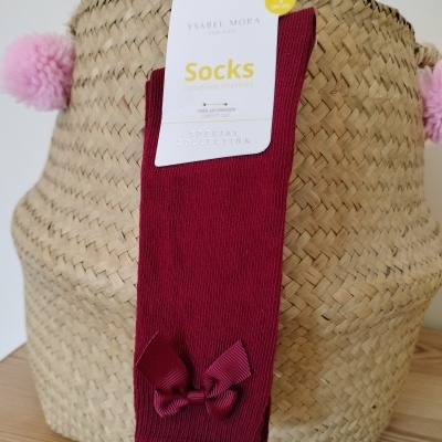 Meias bordô com laço penduradas em saco de palha com pompons cor-de-rosa.