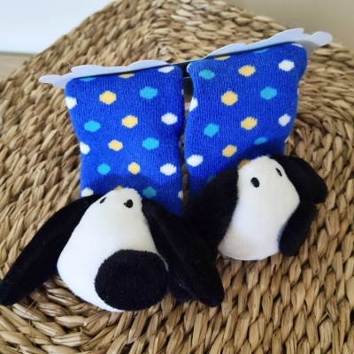 Par de meias azuis com pontos coloridos e peluche em cabeça de cão.