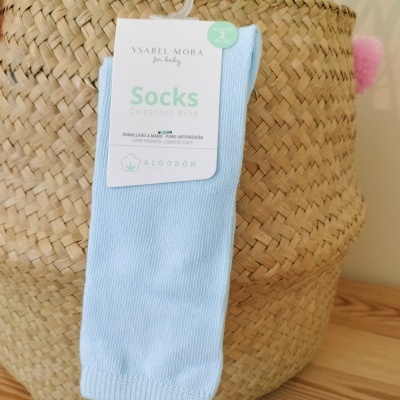 Meias azuis claras para bebé penduradas numa cesta de palha