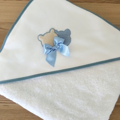 Toalha branca com capuz e borda azul com decoração de ursinhos em crochet e laço azul