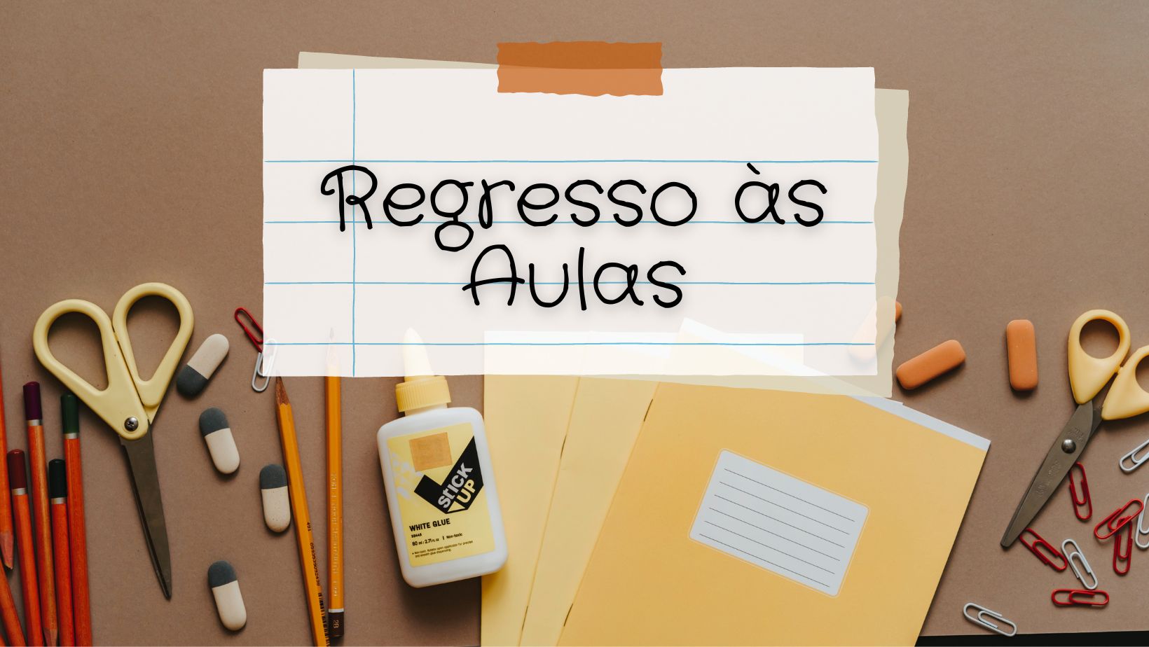 Materiais escolares sobre mesa castanha com nota 'Regresso às Aulas'