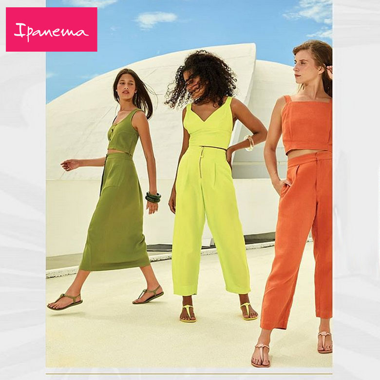 Três mulheres com sandálias e roupas leves coloridas em cenário ao ar livre com logo Ipanema.