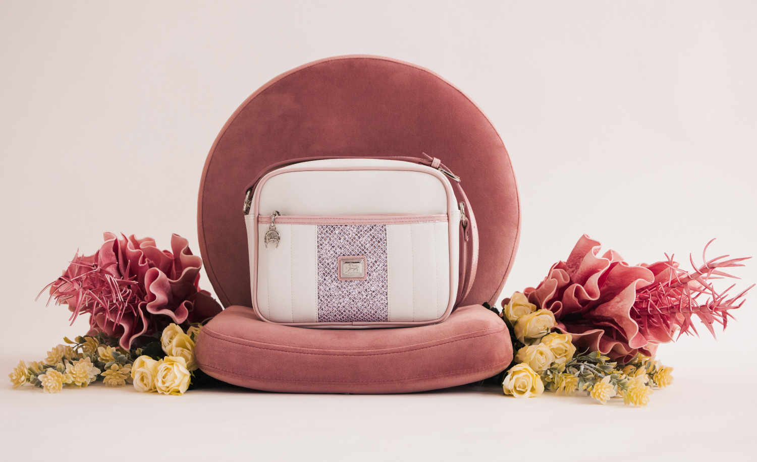 Bolsa de mão branca com padrão azul e almofadas rosas com flores secas