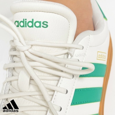 Sapatilha branca Adidas com riscas verdes e sola castanha