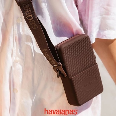 Bolsa castanha pequena com correia larga personalizada usada por cima do ombro.