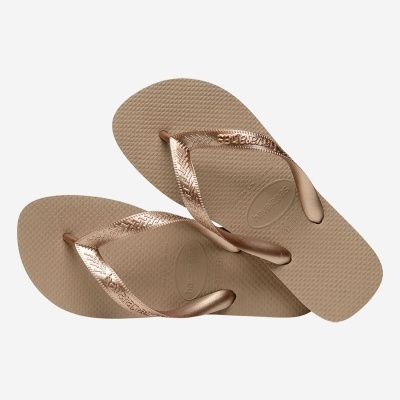 Chinelos havaianas bege com tiras metálicas douradas e logo gravada.