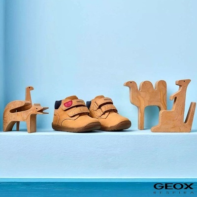 Sapatos bebé castanho claro com esculturas de madeira animais sobre fundo azul e logo Geox