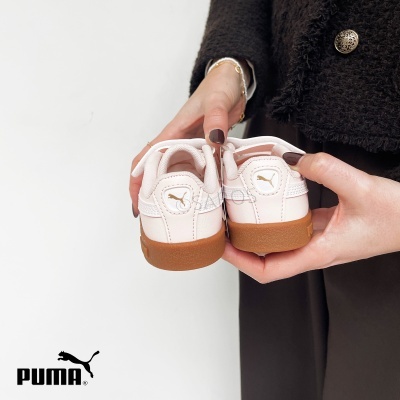 Sapatilhas infantis Puma cor creme com sola castanha nas mãos de uma pessoa