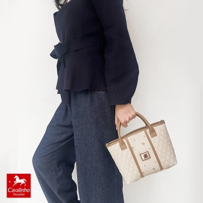 Mulher com mala de mão bege e castanha Cavalinho Penafiel