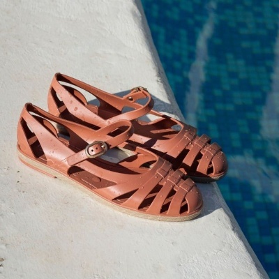Sandálias castanho rosado de plástico com tiras entrelaçadas e fivela junto à piscina