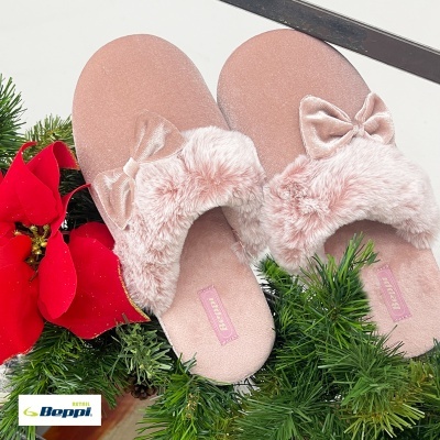Chinelos cor-de-rosa felpudos com laço sobre decoração verde natalícia