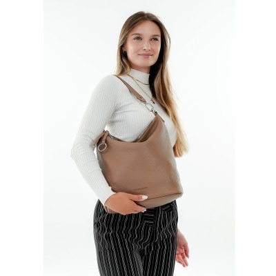 Mala castanha de ombro com textura usada por mulher com camisola branca e calças às riscas pretas
