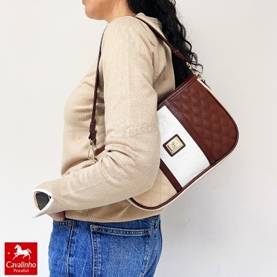Mala de ombro Cavalinho castanha, creme e bege, com padrão matelassê e relevo Cavalinho, usada por pessoa