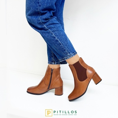 Botins femininos castanhos em pele com salto quadrado e fecho de correr, usados com jeans azuis
