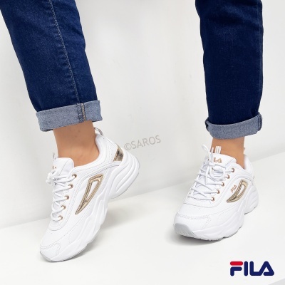 Ténis desportivos brancos FILA com detalhes dourados usados com jeans