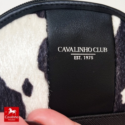 Bolsa com padrão pele de vaca e faixa preta com texto branco