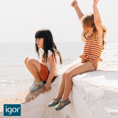 Meninas com roupa de verão e sandálias verdes junto ao mar