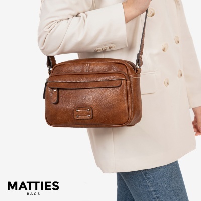 Mala castanha com textura, usada por pessoa com blazer creme e jeans azul