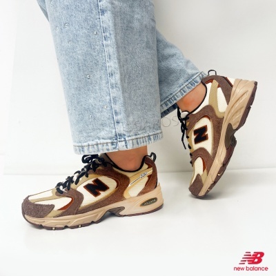 Ténis New Balance castanho, bege e branco com atacadores pretos usados com jeans claros