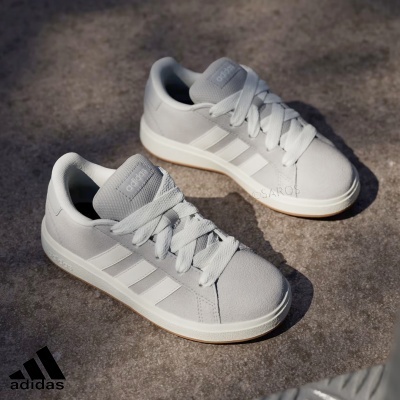 Ténis Adidas cinza claro com riscas brancas e sola branca sobre chão cinza