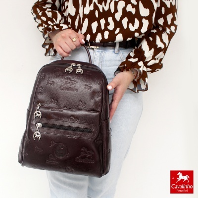 Mochila pequena de pele castanha com padrões de cavalos e o logo Cavalinho