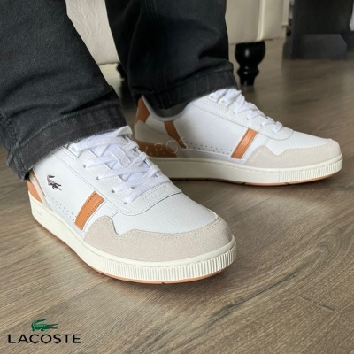 Sapatilhas Lacoste brancas com detalhes castanhos em chão de madeira