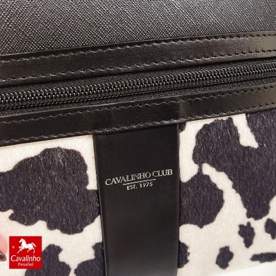 Bolsa preta e branca com padrão de pele de vaca e etiqueta Cavalinho Club