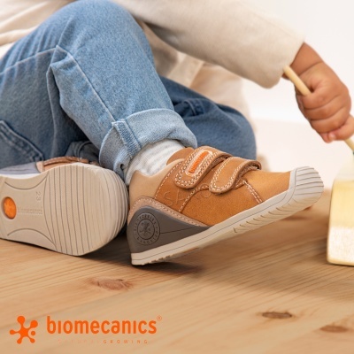 Ténis infantis camurça castanha com velcro e sola cinza em chão de madeira