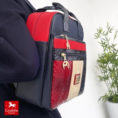 Mochila Cavalinho Penafiel azul, vermelha e bege com texturas variadas e fechos dourados.