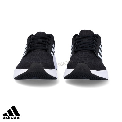 Ténis Adidas pretos com riscas brancas e sola branca vistos de frente