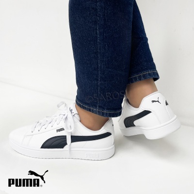 Tênis Puma brancos com detalhes pretos usados com calças de ganga