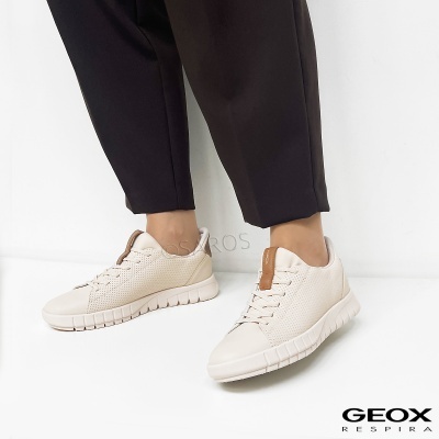 Ténis brancos Geox com detalhe castanho e sola branca, usados com calças pretas