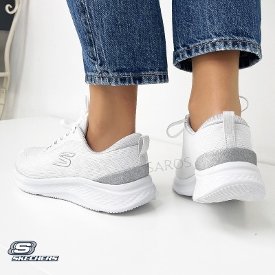 Ténis brancos SKECHERS com detalhes prateados e sola branca usados com jeans azuis