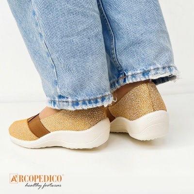 Sapatos femininos Arcopedico castanhos com padrão branco e detalhe elástico, usados com jeans azul claro.