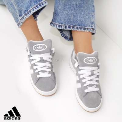 Ténis Adidas cinza com cadarços brancos usados com jeans azuis