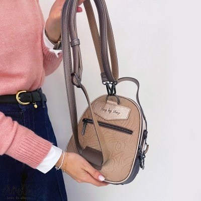 Mala de mão castanha clara com etiqueta step by step e alça dupla regulável, segurada por pessoa com camisola rosa