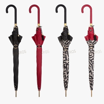 Quatro guarda-chuvas longos, dois pretos e dois com padrão geométrico preto e branco, detalhes dourados e cabos curvos