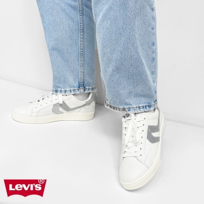 Ténis brancos com detalhe cinza brilhante usados com calças de ganga claras