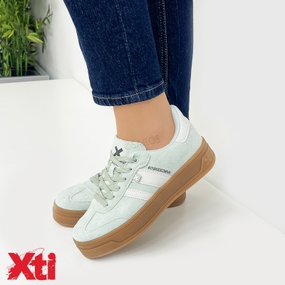 Ténis verde-água Xti com sola castanha, detalhes brancos e atacadores, usados com jeans