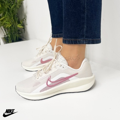 tênis desportivos brancos com detalhes rosa e sola branca usados com jeans escuros