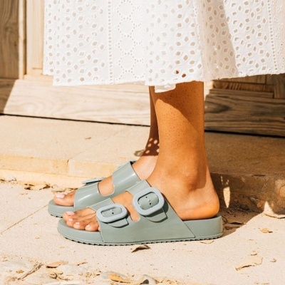 Sandálias verdes com duas fivelas em pavimento de pedra