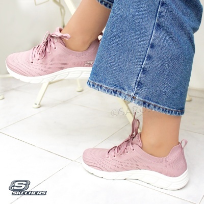Ténis Skechers cor de rosa com sola branca usados por pessoa com calças de ganga.