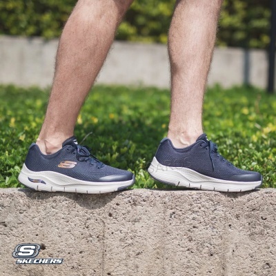 Tênis azuis Skechers com sola branca usados numa superfície de betão outdoors