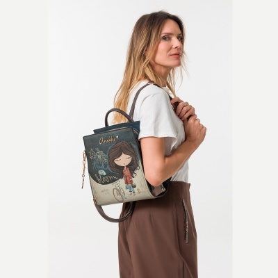 Mochila com ilustração colorida e alças castanhas usada por mulher com t-shirt branca