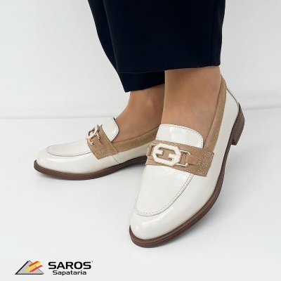 Sapatos mocassins brancos com detalhe castanho e fivela dourada, usados por modelo com calças pretas