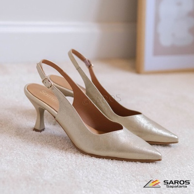 Sapatos de salto alto dourados com alças traseiras ajustáveis sobre tapete claro