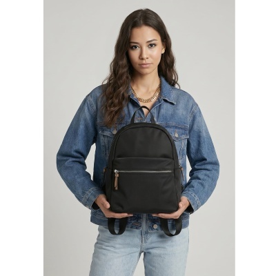 Mochila preta com fecho prateado e detalhes castanhos, segurada por mulher com casaco de ganga azul