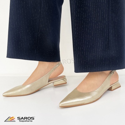 Sapatos dourados de senhora com salto baixo e tiras, usados com calças azul-escuras com risca de giz